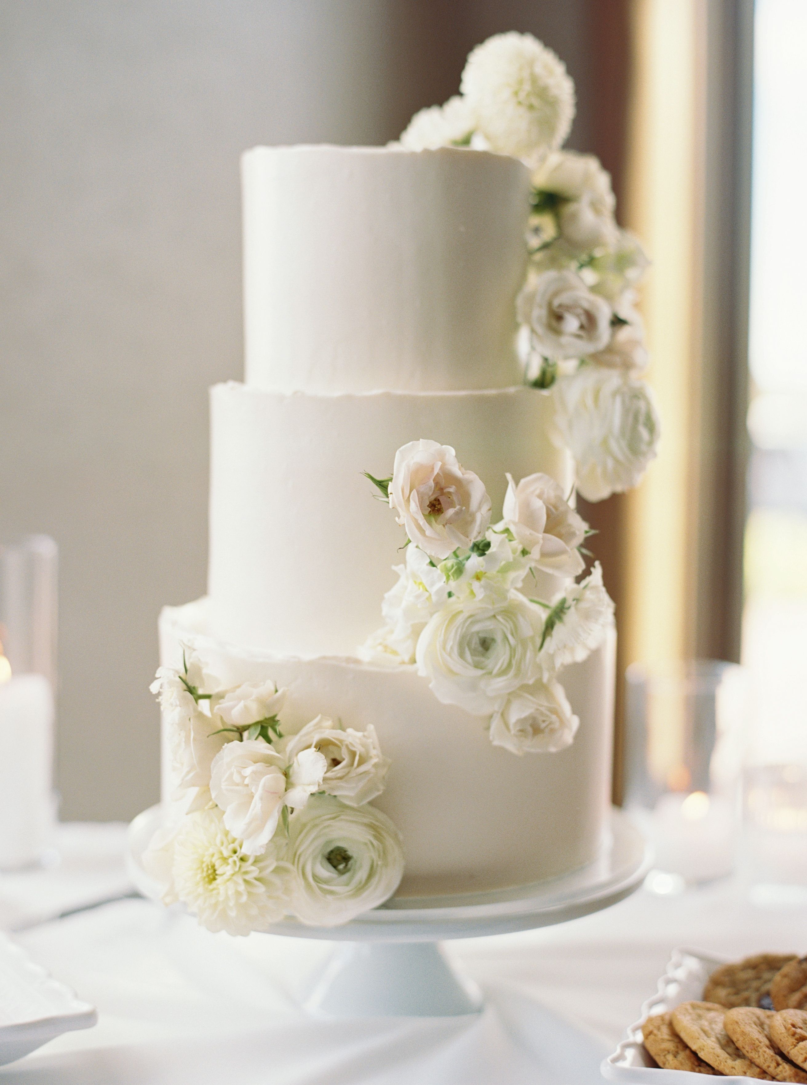 Smooth white buttercream three tier cake with fresh flowers on each tier