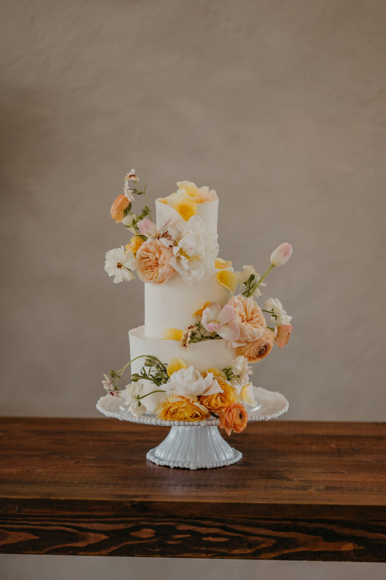 Three tier white wedding cake with fresh flowers